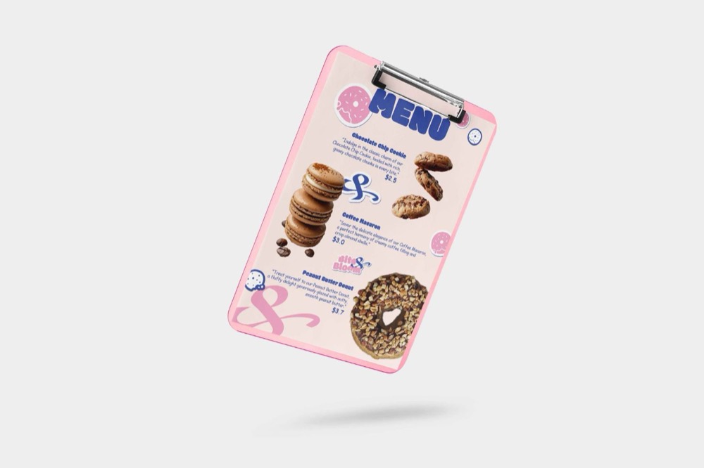 Menu dạng bảng kẹp màu hồng của BITE & BLOOM với tiêu đề MENU xanh cobalt, ảnh bánh quy, macaron và donut kèm mô tả và giá