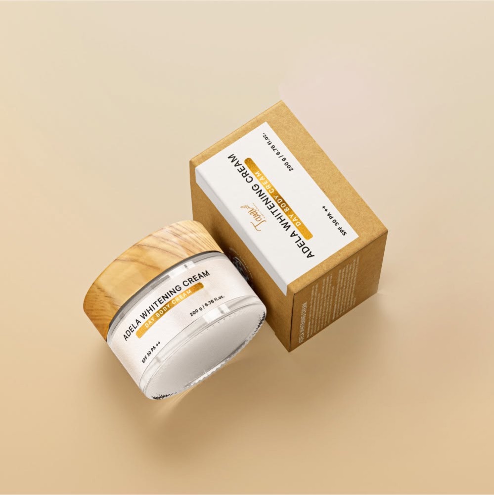 Hũ kem ADELA WHITENING CREAM nắp vân gỗ cạnh hộp giấy kraft có nhãn trắng và dải chữ ánh kim vàng của TAMI